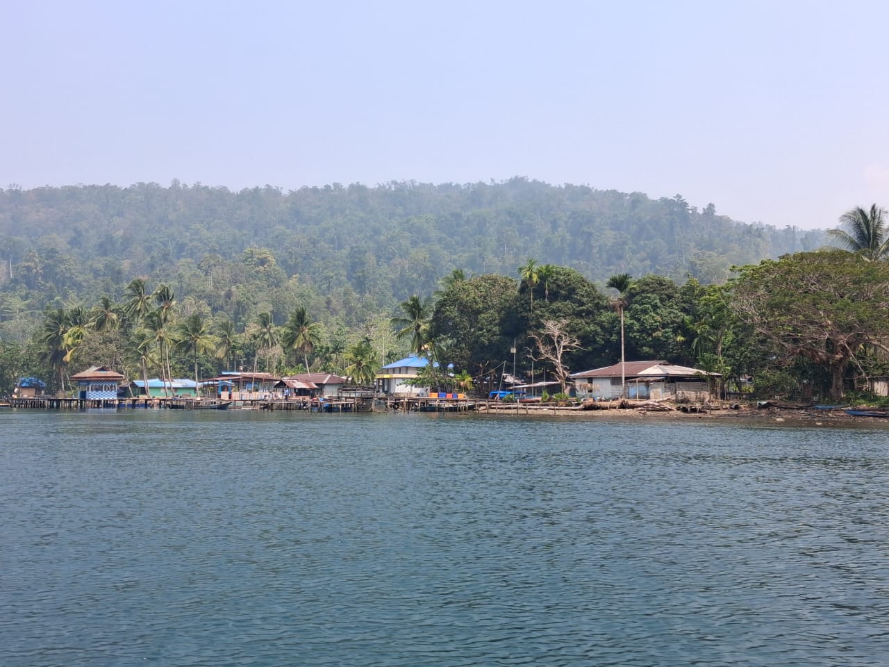 Lopintol village on the shores of Mayalibit Bay, with forested hills behind the waterfront